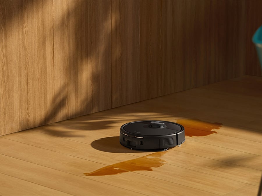 Robot sprzątający Roborock Q7 TF Black czyści rozlaną ciecz na drewnianej podłodze w nowoczesnym wnętrzu
