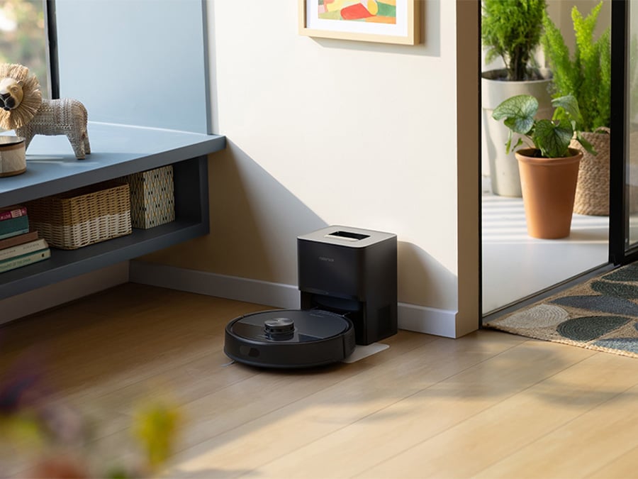 Robot sprzątający Roborock Q7 TF Black wraca do stacji dokującej stojącej przy ścianie w jasnym, przytulnym wnętrzu