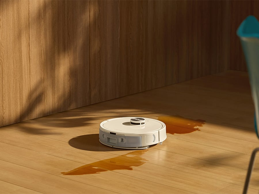 Robot sprzątający Roborock Q7 TF White czyści rozlaną ciecz na drewnianej podłodze w nowoczesnym wnętrzu