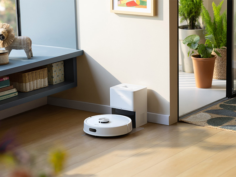 Robot sprzątający Roborock Q7 TF White wraca do stacji dokującej stojącej przy ścianie w jasnym, przytulnym wnętrzu