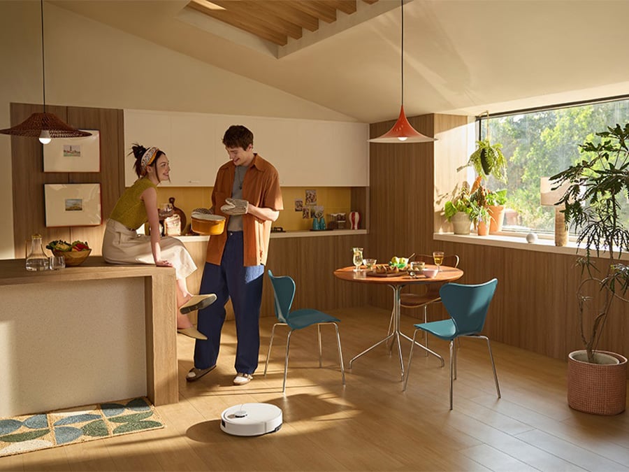Para w kuchni rozmawiająca przy posiłku, a robot sprzątający Roborock Q10 samodzielnie porusza się po podłodze, omijając przeszkody