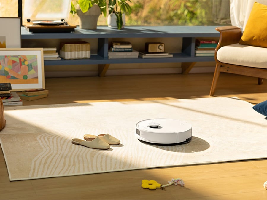 Robot sprzątający Roborock Q10 PF White odkurza jasny dywan w nowoczesnym wnętrzu z jasnym drewnianym parkietem