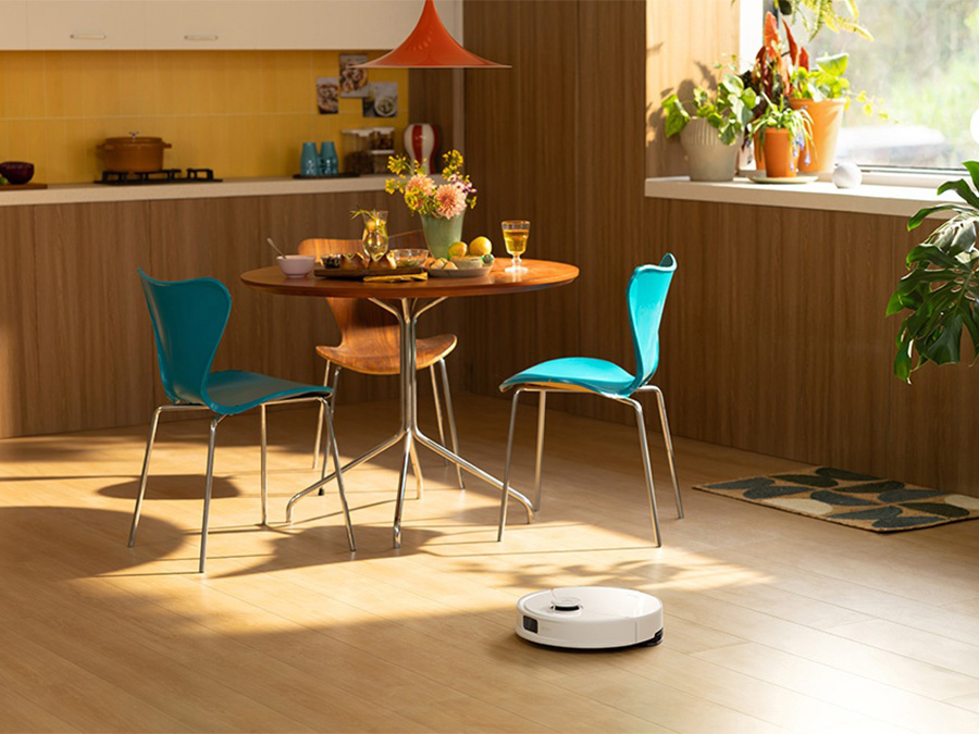 Robot sprzątający Roborock Q10 PF White odkurza przestrzeń przy jadalnianym stole z turkusowymi krzesłami