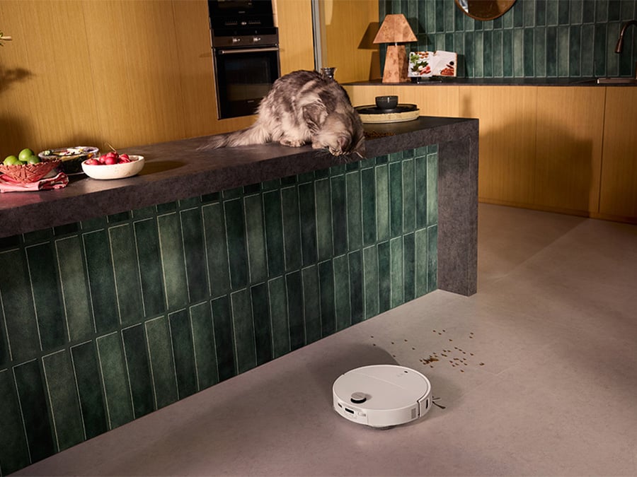 Kobieta i mężczyzna spędzają czas w salonie z kotem, podczas gdy robot sprzątający Roborock Qrevo Edge T White cicho odkurza podłogę drewnianą