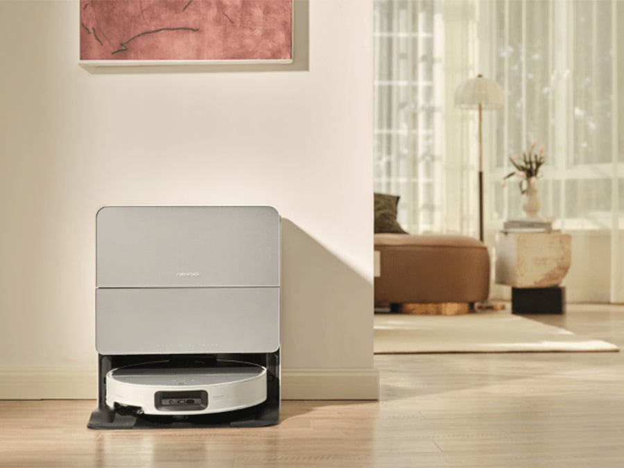 Robot sprzątający Roborock Saros 10 White znajdujący się w nowoczesnej stacji dokującej ustawionej przy ścianie w jasnym, przestronnym salonie