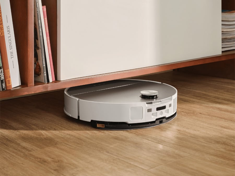 Robot sprzątający Roborock Saros 10 White dokładnie odkurzający przestrzeń pod niską szafką z półkami na książki