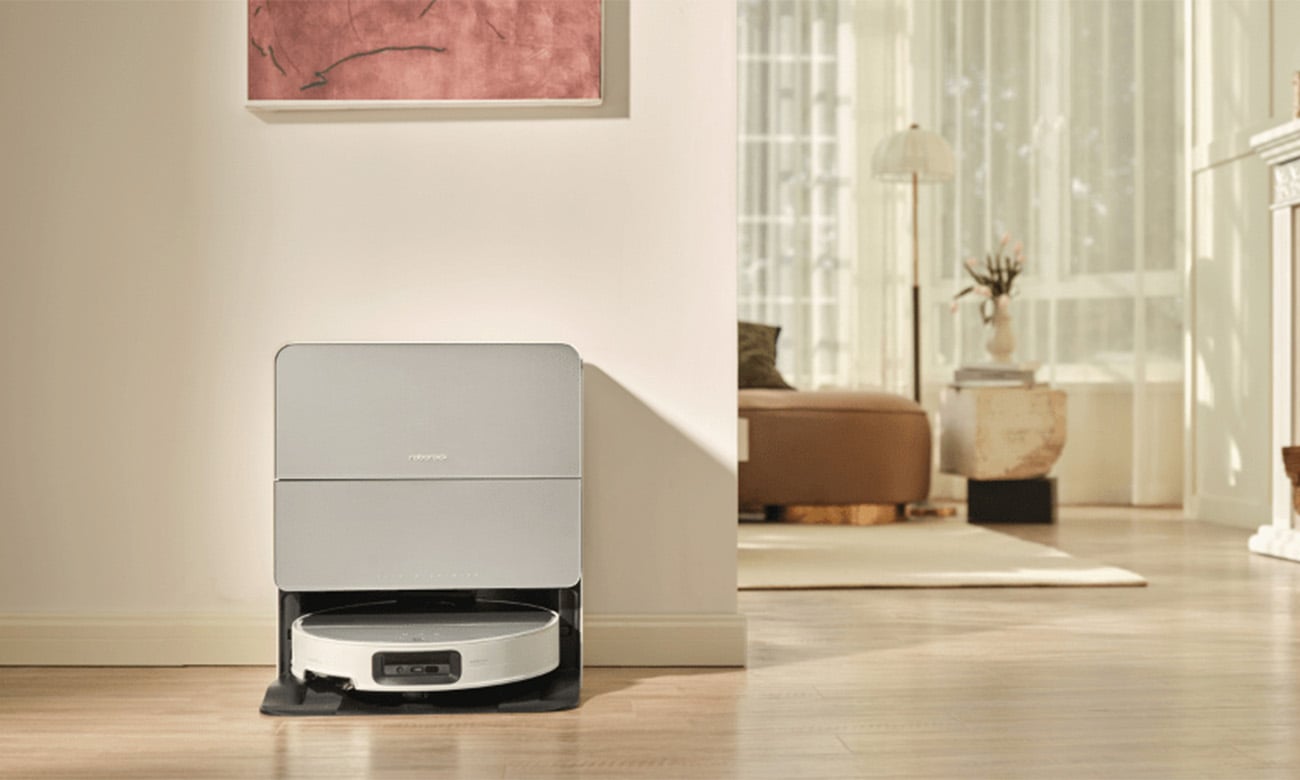 Robot sprzątający Roborock Saros 10 White znajdujący się w nowoczesnej stacji dokującej ustawionej przy ścianie w jasnym, przestronnym salonie