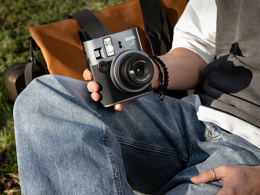 Użytkownik siedzący na ławce trzymający Fujifilm Instax mini 41 w dłoni