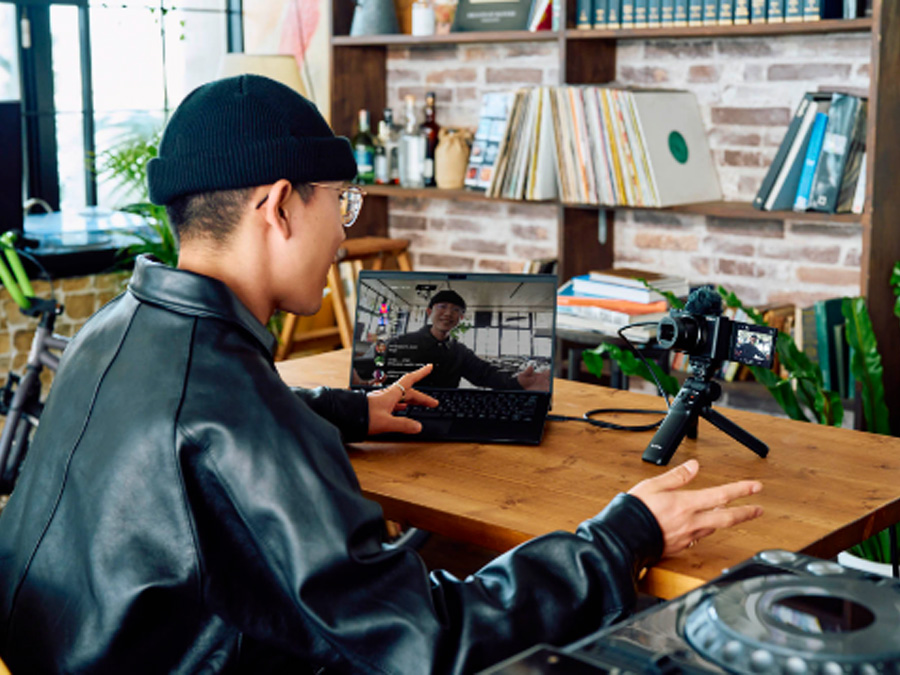 Osoba prowadząca transmisję na żywo z użyciem aparatu Sony ZV-1 II podłączonego do laptopa